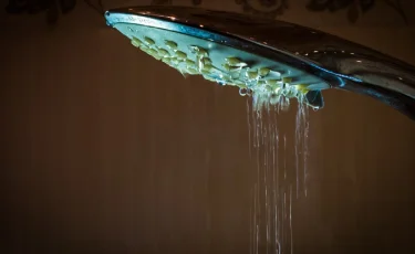 Девушка со слезами на глазах принимает душ из-за аллергии на воду