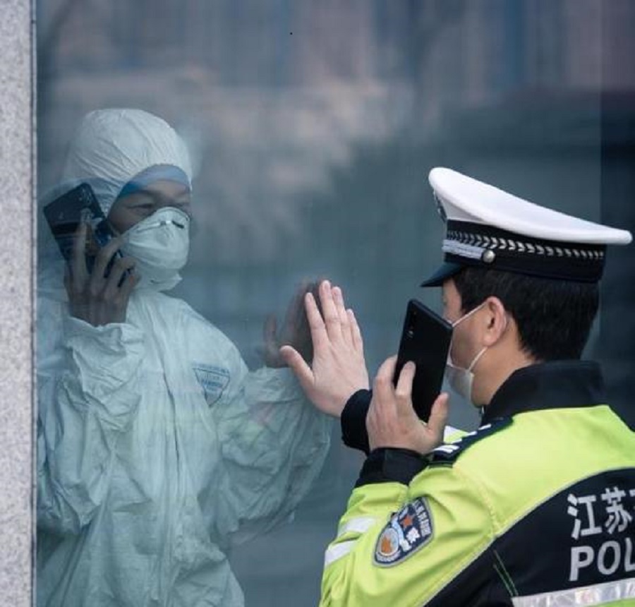 Вирусное фото: китайский полицейский и его жена общаются через стекло карантинного отделения